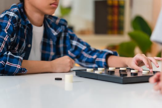 Asian teenage girl and boy playing board game, Asian brother and sister relaxing hobbies playing a game of checkers in living room photo