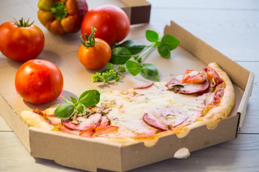 cooked pizza with salami and sausage in a box on a wooden table photo