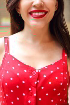 Smiling attractive girl in red polka dots dress in park photo