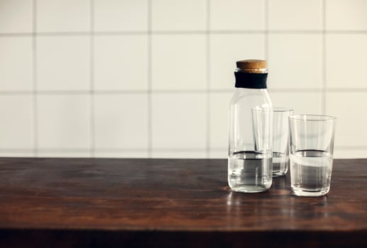 Transparent bottle and glasses with mineral water on wooden table photo
