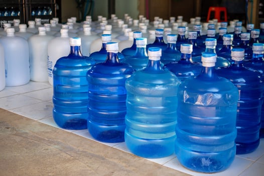 Many blue gallons and white gallon of drinking water are lined up in a drinking water production plant. photo