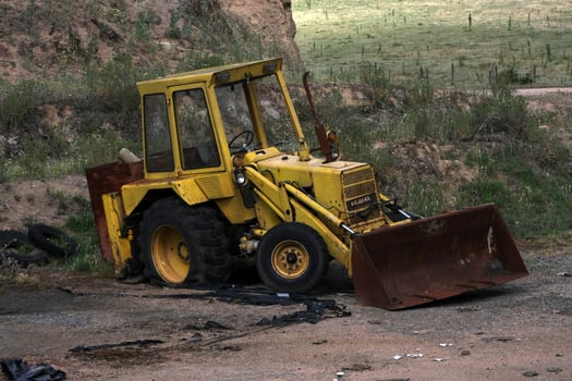 Abandoned backhoe excavator rusting in a forgotten construction site, showcasing years of neglect and decay. photo