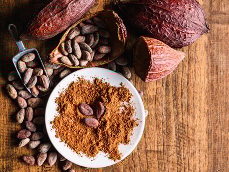 Top view of Natural cocoa powder with brown cocoa beans and dry cacao pod on a vintage wooden table. photo