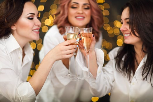 Smiling women in white shits with glasses of champagne over lights background photo