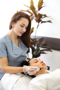 Female beautician using machine for microcurrent treatment photo