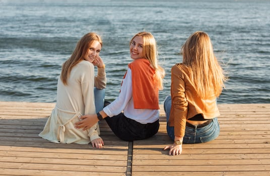 Happy girlfriends resting on pier near water photo