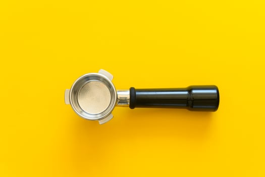 Empty espresso portafilter on a yellow background photo