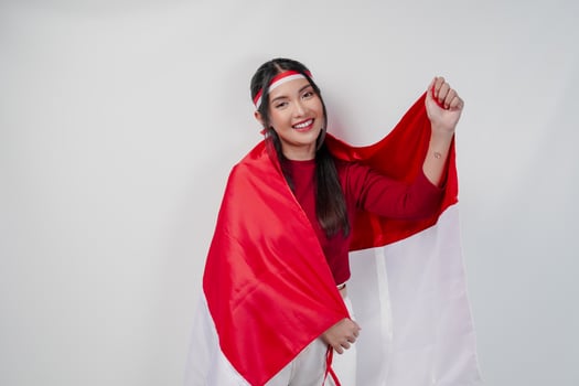 Confident Asian woman is covering herself with Indonesian flag and raising a fist. photo