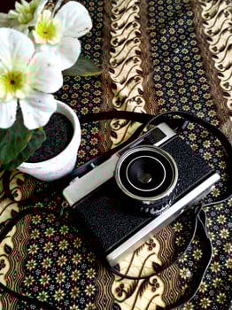 old film camera gear isolated on a traditional Indonesian kain batik patern background. retro photography vintage. nostalgic vacation historical moment photo