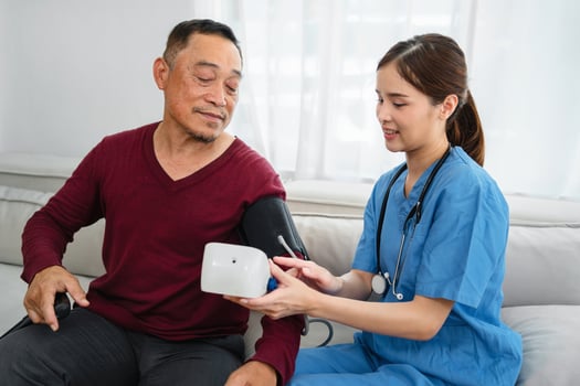 woman in a blue scrubs is helping a man with a blood pressure cuff photo