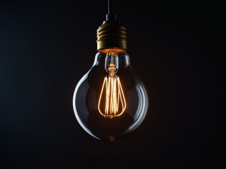 Luminous light bulb emphasizing electricity conservation on contrasting dark backdrop. photo