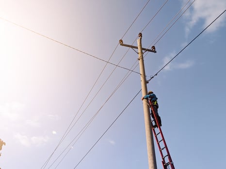 Asian electricians are climbing on electric poles to install and repair power lines. photo