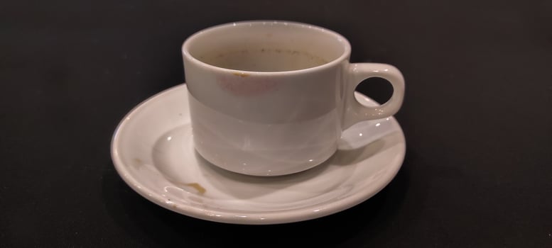 White coffee in mug with saucer on black background photo