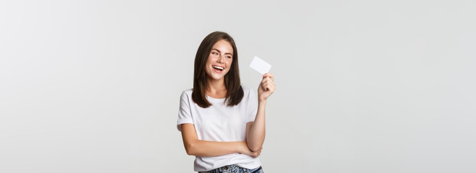 Attractive happy brunette girl laughing and holding credit card, white background photo
