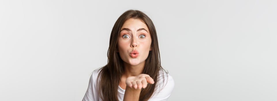 Close-up of beautiful flirty girl pouting lips and sending air kiss at camera photo