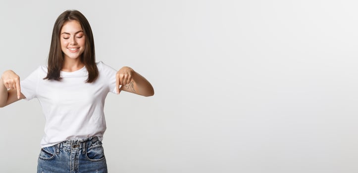 Excited happy brunette girl, looking and pointing down with satisfied smile photo