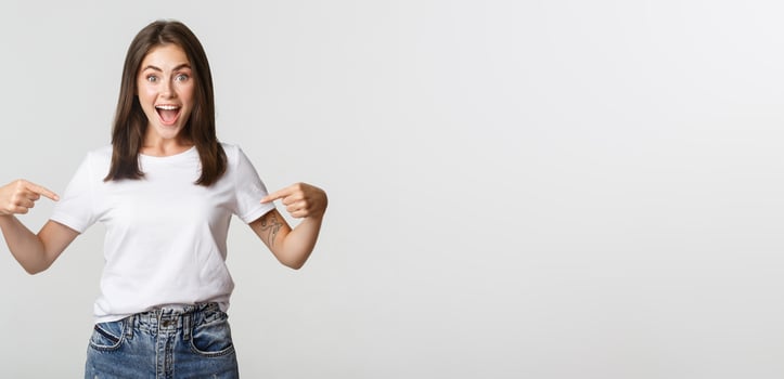Excited happy brunette girl smiling, pointing fingers at logo, showing banner photo