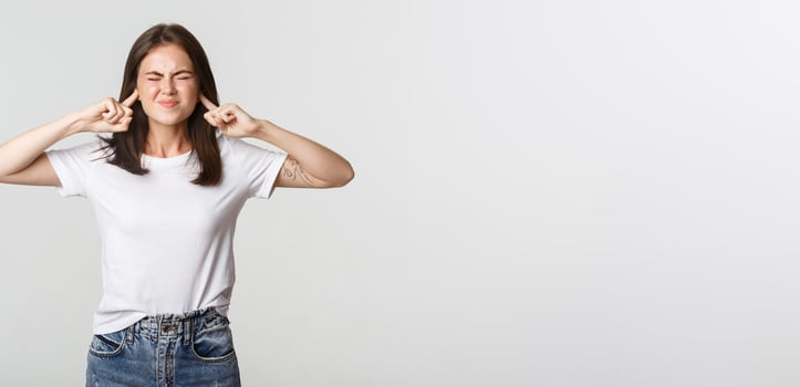 Annoyed brunette girl grimacing, shut ears with fingers from loud noise photo