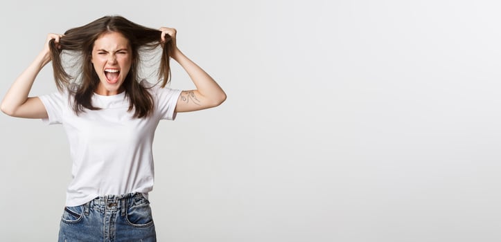 Outraged mad young woman ripping hair on head and yelling angry photo