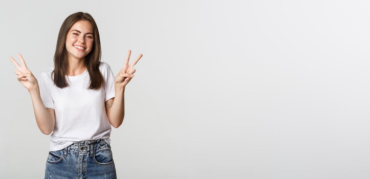 Cheerful attractive young woman smiling, showing peace gestures photo