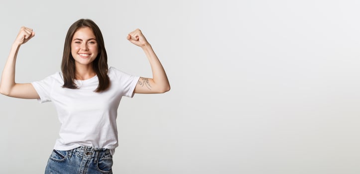 Portrait of confident attractive girl flex biceps to show strengths, smiling sassy photo