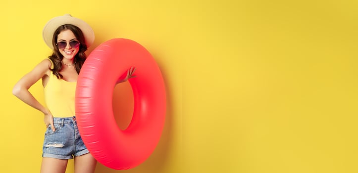 Stylish beach girl with swimming ring, laughing and smiling on summer vacation, sea trip, standing happy against yellow background photo