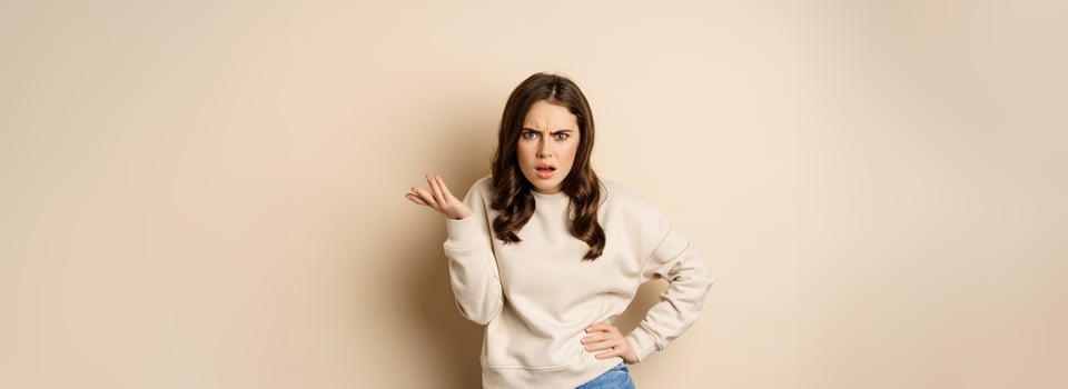 Frustrated and pissed-off woman, looking confused, arguing, standing over beige background photo