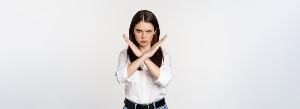 Serious woman showing stop sign, disagree, rejecting smth bad, standing over white background photo
