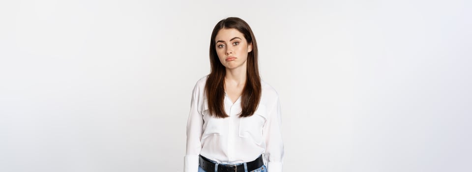 Sad and gloomy woman sulking, looking disappointed and moody, standing upset against white background photo