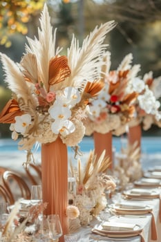 A beautifully decorated outdoor table with bouquets of orchids, dry flowers, pampas grass luxury tableware and cutlery photo