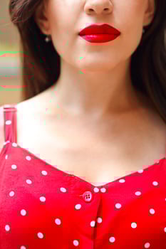 Smiling attractive girl in red polka dots dress in park photo
