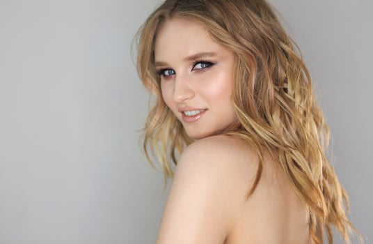 Young beautiful woman with blonde curly hair on grey background photo