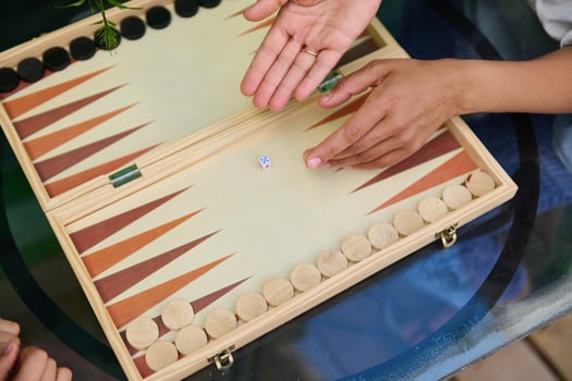 Close-up of hands playing backgammon on wooden board game outdoors photo