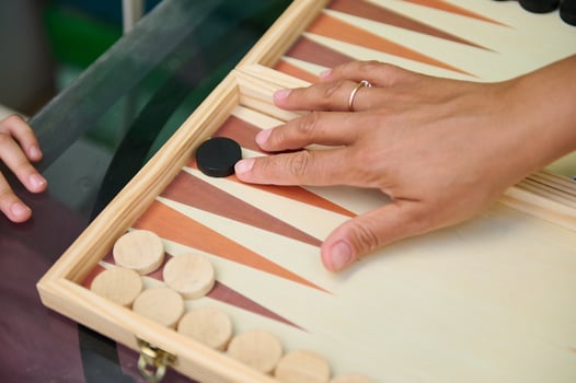 Close-up of hands playing backgammon on wooden board, showcasing strategic game move photo