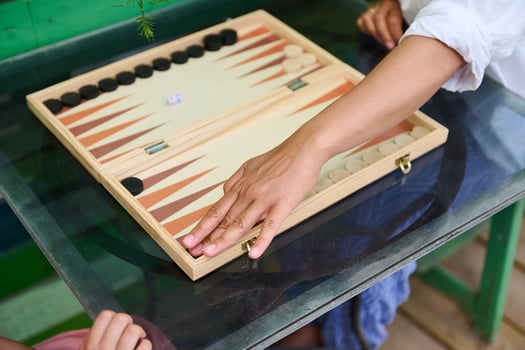 People playing backgammon on glass table, a classic board game for leisure and fun photo