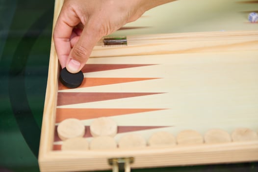 Hand placing chip in backgammon game on wooden board photo