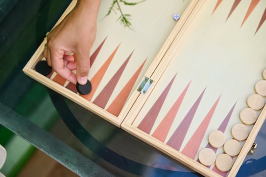 Hand placing a game piece on a backgammon board during an outdoor game session photo