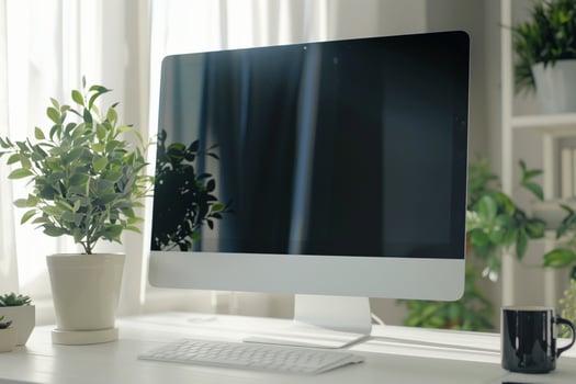 Computer mockup on a white desk with a plant and  background photo