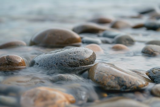 Smooth pebble textures on a riverbed with flowing water photo