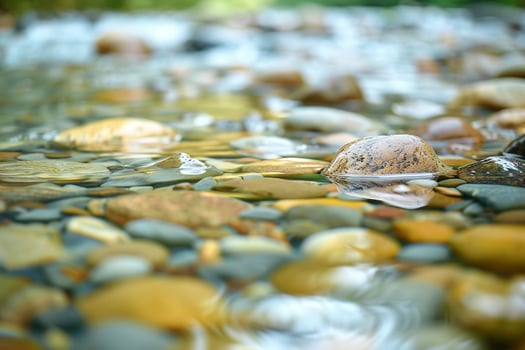 Smooth pebble textures on a riverbed with flowing water photo