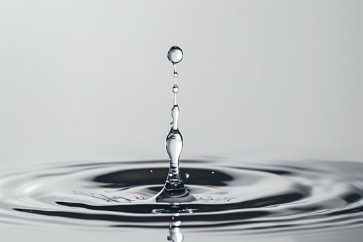 Single Water Droplet Falling into a Pool of Water Creating Gentle Ripples photo