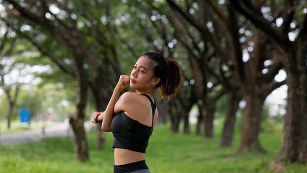 A woman is stretching her leg on a sidewalk next to a pole photo