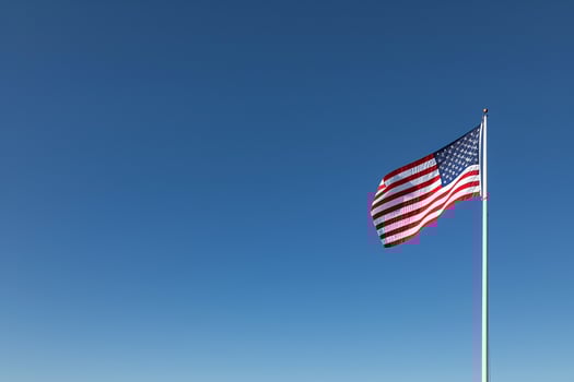 American Flag Billowing in a   Blue Sky Symbolizing National Pride and Unity photo