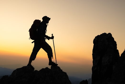 Silhouette of Man hiking on mountain with backpack hiking in the mountains at sunset photo