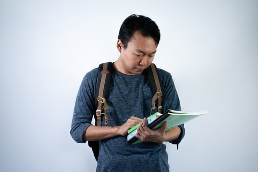 Asian young male student wearing bag and carrying books smiling and happy expression with isolated white background photo
