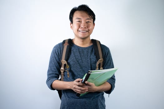 Asian young male student wearing bag and carrying books smiling and happy expression with isolated white background photo