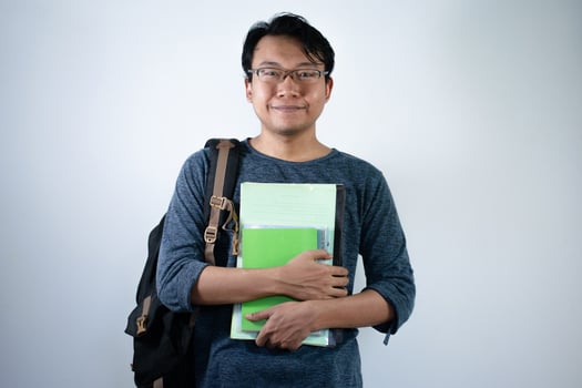 Asian young male student wearing bag and carrying books smiling and happy expression with isolated white background photo