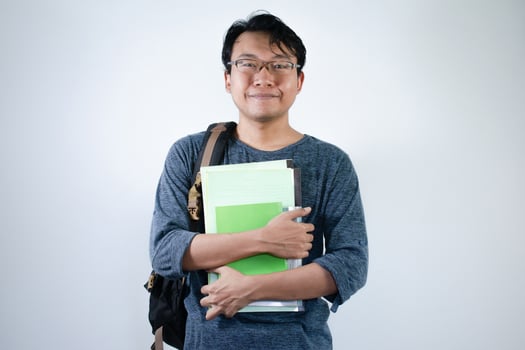 Asian young male student wearing bag and carrying books smiling and happy expression with isolated white background photo