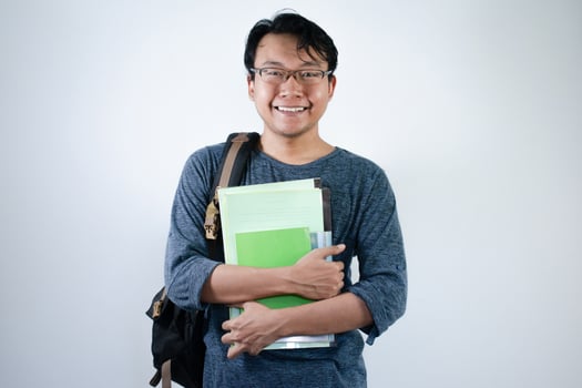 Asian young male student wearing bag and carrying books smiling and happy expression with isolated white background photo
