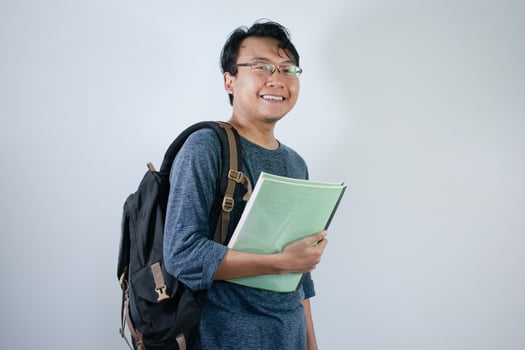 Asian young male student wearing bag and carrying books smiling and happy expression with isolated white background photo
